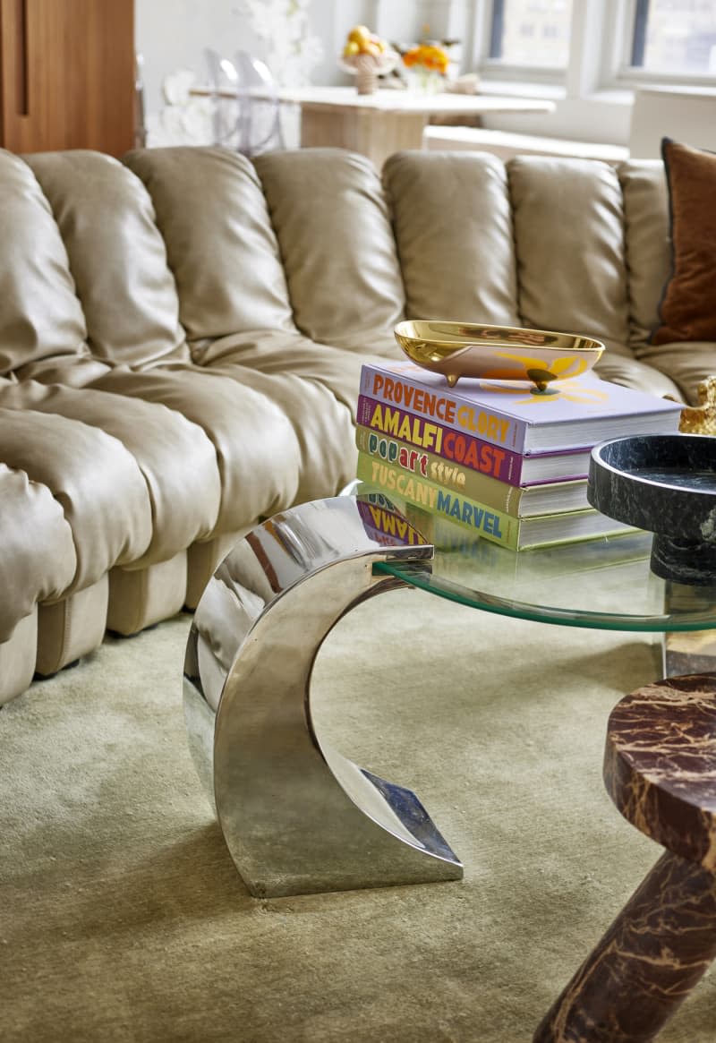 Stack of design books on glass coffee table in living room.