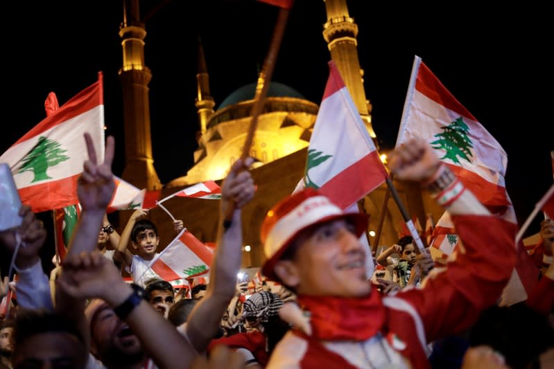 Protesters gesture as they wave flags at a demonstration during ongoing anti-government protests in Beirut