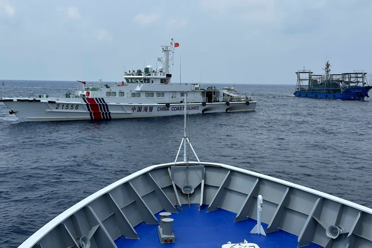 A Chinese coast guard ship, left, with a Chinese militia vessel, right, blocks Philippine coast guard ship, ‘BRP Sindangan’, as it tried to head towards Second Thomas Shoal at the disputed South China Sea during rotation and resupply mission  (AP)