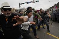 Supporters of former President Pedro Castillo confront riot police surrounding the police station where Castillo arrived earlier, in Lima, Peru, Wednesday, Dec. 7, 2022. Peru's Congress removed Castillo from office Wednesday, voting to replace him with the vice president, shortly after Castillo decreed the dissolution of the legislature ahead of a scheduled vote to oust him. (AP Photo/Martin Mejia)