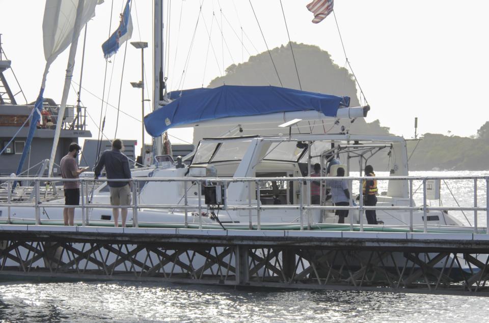 Relatives stand nearby as investigators from Grenada and St. Vincent and the Grenadines stand aboard the yacht "Simplicity," which they say was hijacked by three escaped prisoners with two people on board, now anchored at the St. Vincent and the Grenadines Coast Guard Calliaqua Base, in Calliaqua, St. Vincent, Friday, Feb. 23, 2024. Authorities in the eastern Caribbean said they were trying to locate two people believed to be U.S. citizens who were aboard the yacht that was hijacked by the three escaped prisoners from Grenada.(AP Photo/Kenton X. Chance)