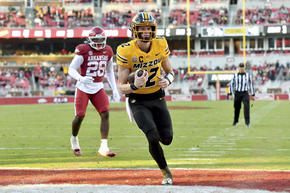 Missouri quarterback Brady Cook (12) runs past Arkansas linebacker Jaheim Thomas (28) to score a touchdown during the first half of an NCAA college football game Friday, Nov. 24, 2023, in Fayetteville, Ark. (AP Photo/Michael Woods)