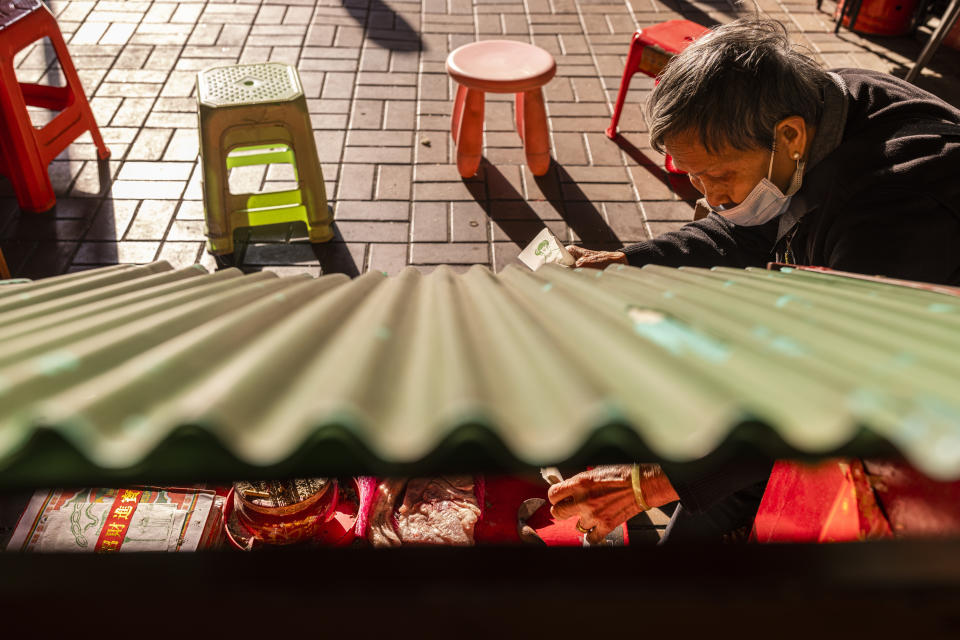 A practitioner prepares papers with image of a villain at a "villain hitting" booth under the Canal Road Flyover in Hong Kong, on Sunday, March 5, 2023. (AP Photo/Louise Delmotte)