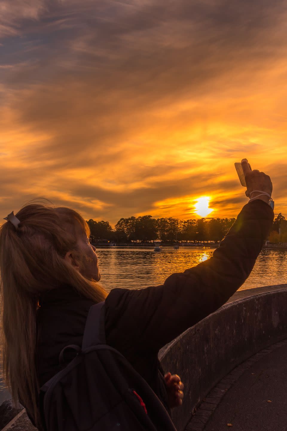adult woman taking a selfie in the evening with the lake behind her