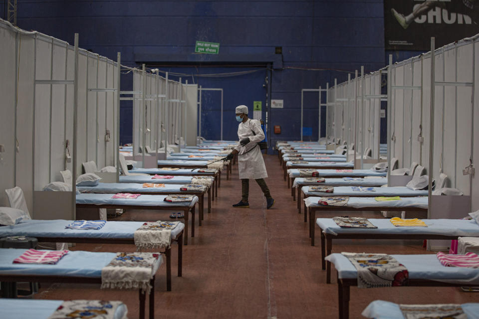 A man sanitizes a makeshift COVID-19 care center at an indoor sports stadium in New Delhi, India, Wednesday, July 8, 2020. India has overtaken Russia to become the third worst-affected nation by the coronavirus pandemic. (AP Photo/Altaf Qadri)