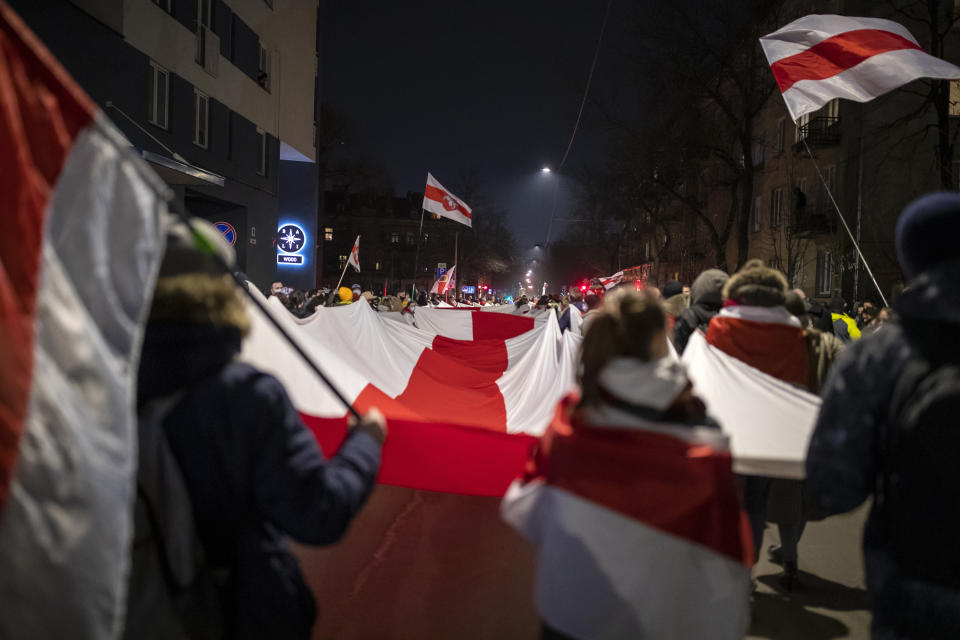 Belarusian people carry a giant historical flag of Belarus during a celebration for the 103rd anniversary of the declaration of the Belarusian People's Respublic, in Vilnius, Lithuania, Thursday, March 25, 2021. Freedom Day is an unofficial holiday in Belarus celebrated on 25 March to commemorate the declaration of independence by the Belarusian Democratic Republic on that date in 1918.(AP Photo/Mindaugas Kulbis)