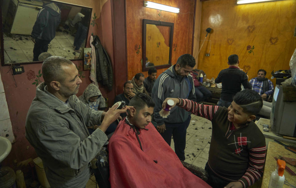 Men wait at a barber shop for their turn to get a haircut, in preparation for the Coptic Christmas celebration, at a residential and industrial area of eastern Cairo, Egypt, Monday, Jan. 6, 2020. (AP Photo/Hamada Elrasam)