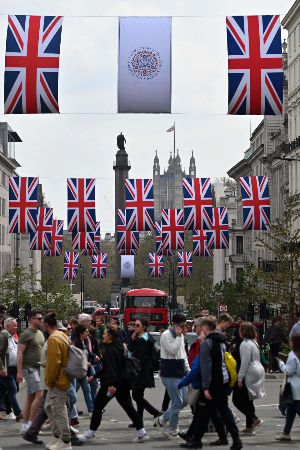 People walk beneath Union flags and Coronation Emblem flags in central London, on April 30, 2023, ahead of the coronation ceremony of Charles III and his wife, Camilla, as King and Queen of the United Kingdom and Commonwealth Realm nations, on May 6, 2023.