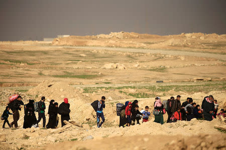 Displaced Iraqi people, who fled their homes during a battle between Iraqi forces and Islamic State militants, carry their belongings in Mosul, Iraq March 9, 2017. REUTERS/Thaier Al-Sudani