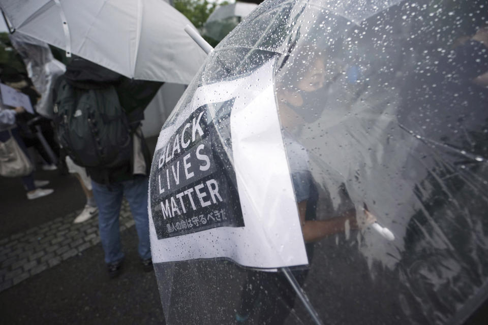 A protester, with a banner seen through her umbrella, take part in a solidarity rally for the death of George Floyd in Tokyo Sunday, June 14, 2020. Floyd died after being restrained by Minneapolis police officers on May 25. (AP Photo/Eugene Hoshiko)