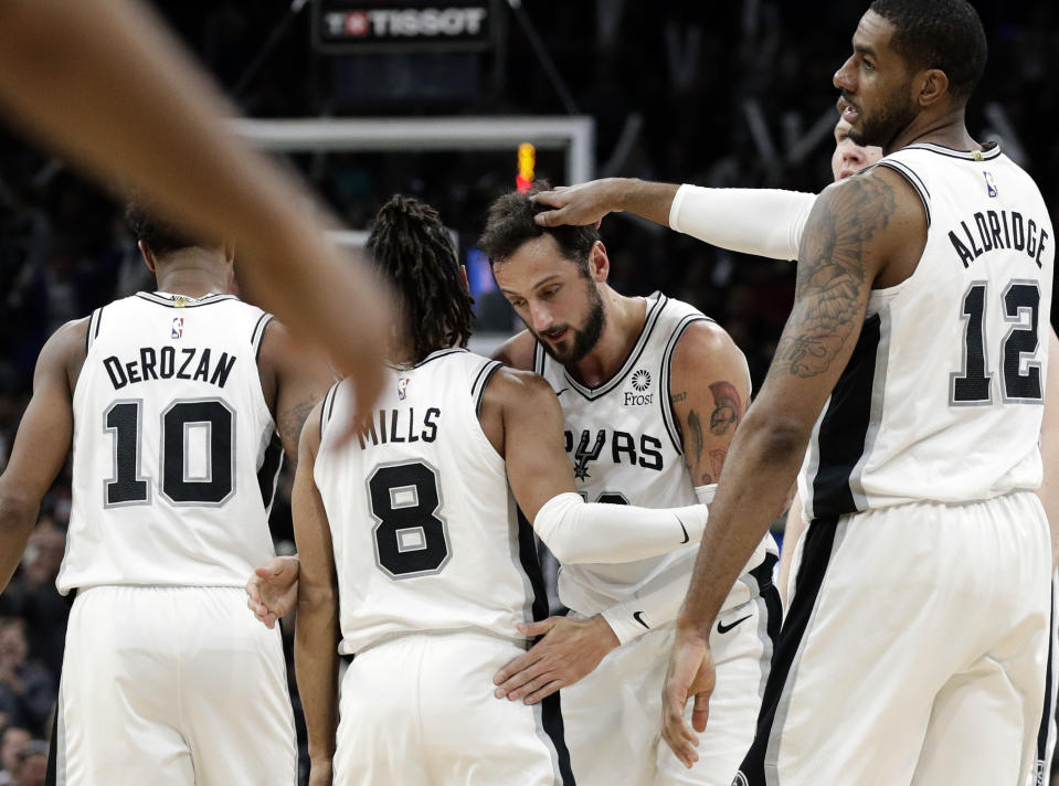 San Antonio Spurs guard Marco Belinelli, third from left, celebrates with teammates DeMar DeRozan (10), Patty Mills (8), LaMarcus Aldridge (12) and Davis Bertans, back right, after scoring against the Golden State Warriors during the second half of an NBA basketball game in San Antonio, Monday, March 18, 2019. (AP Photo/Eric Gay)