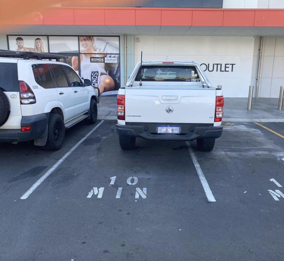 The white ute parked over the bay's white line.