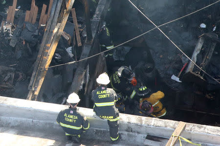 Firefighters work inside the burned warehouse following the fatal fire in the Fruitvale district of Oakland, California, U.S. December 4, 2016. REUTERS/Lucy Nicholson