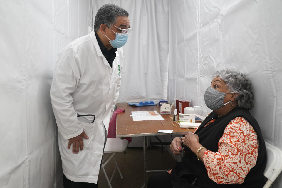 El doctor Víctor Peralta, a la izquierda, habla con Nellie Hernández, antes de inyectarle la segunda dosis de la vacuna contra la COVID-19 en Nueva York, el viernes 5 de febrero del 2021. Desde ancianos cubanos-estadounidenses en la Florida hasta campesinos de California, los latinos enfrentan fuertes obstáculos para recibir las vacunas contra el COVID-19 en Estados Unidos, creando riesgos para la salud pública a medida que el virus cambia y se propaga. (Foto AP/Seth Wenig)