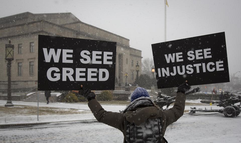A woman holds up signs as she stands in quiet protest outside the War Memorial building in Trenton, New Jersey January 21, 2014. Governor Chris Christie is being sworn in today for his second term. (REUTERS/Carlo Allegri)