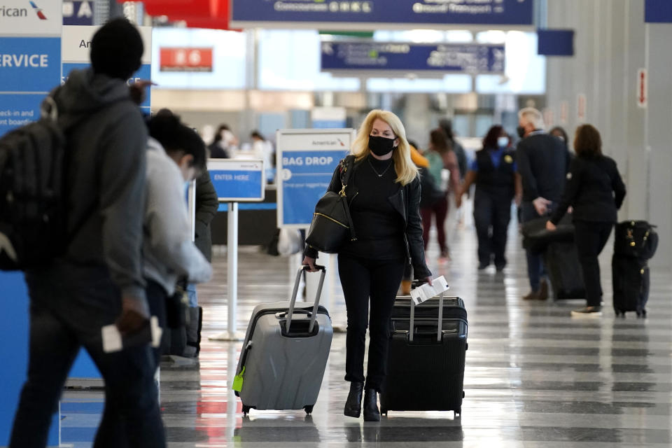 FILE - In this Sunday, Nov. 29, 2020 file photo, a traveler wears a mask as she walks through Terminal 3 at O'Hare International Airport in Chicago. The Transportation Security Administration said nearly 1.2 million people went through U.S. airports on Sunday, the highest number since the coronavirus pandemic gripped the country back in March, despite the pleadings of public health experts for people to stay home over Thanksgiving. (AP Photo/Nam Y. Huh, File)