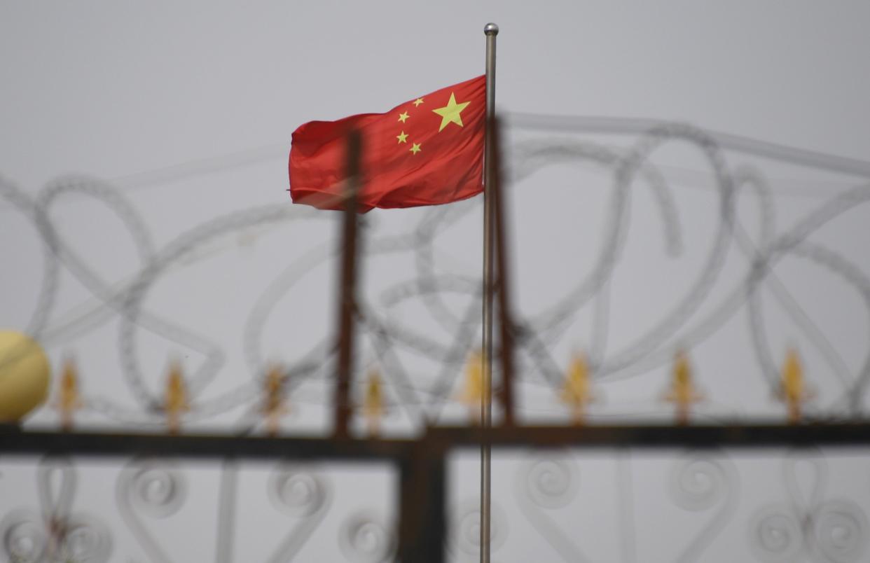 The Chinese flag behind razor wire at a housing compound in Yangisar, south of Kashgar, in China’s western Xinjiang region (AFP via Getty Images)