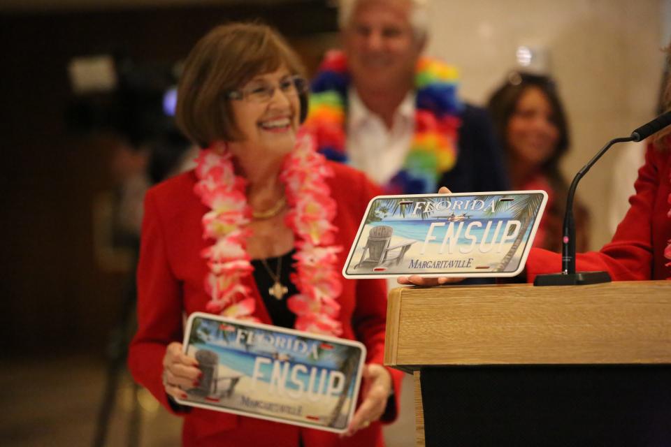 Sen. Gayle Harrel, R- Jupiter, smiles and holds the Jimmy Buffet specialty license plate prototype inside the Florida Capitol, Jan. 25, 2024.