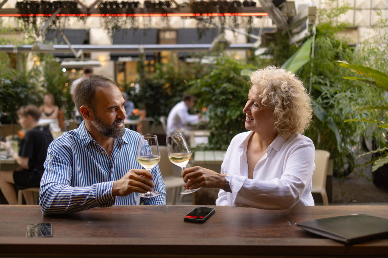 Happy mid adult couple communicating while toasting with white wine in a restaurant.