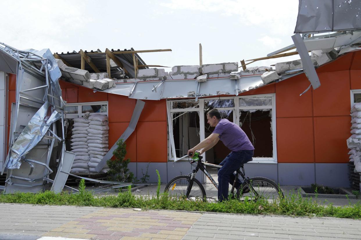 A man cycles past a building damaged by strikes in the town of Shebekino, near the Ukrainian border in the Belgorod region (AFP via Getty Images)
