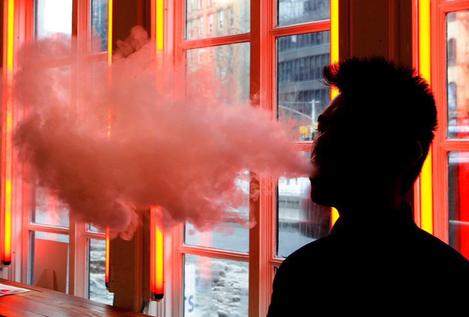 FILE - In this Feb. 20, 2014, file photo, a patron exhales vapor from an e-cigarette at a store in New York. Only two years ago e-cigarettes were viewed as holding great potential for public health: offering a way to wean smokers off traditional cigarettes. But now Juul and other vaping companies face an escalating backlash that threatens to sweep their products off the market. (AP Photo/Frank Franklin II, File)