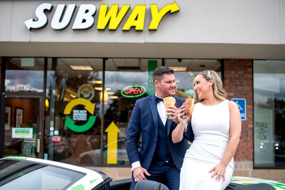 Julie Bushart &amp; Zack Williams pose with sandwiches outside of Subway Restaurant