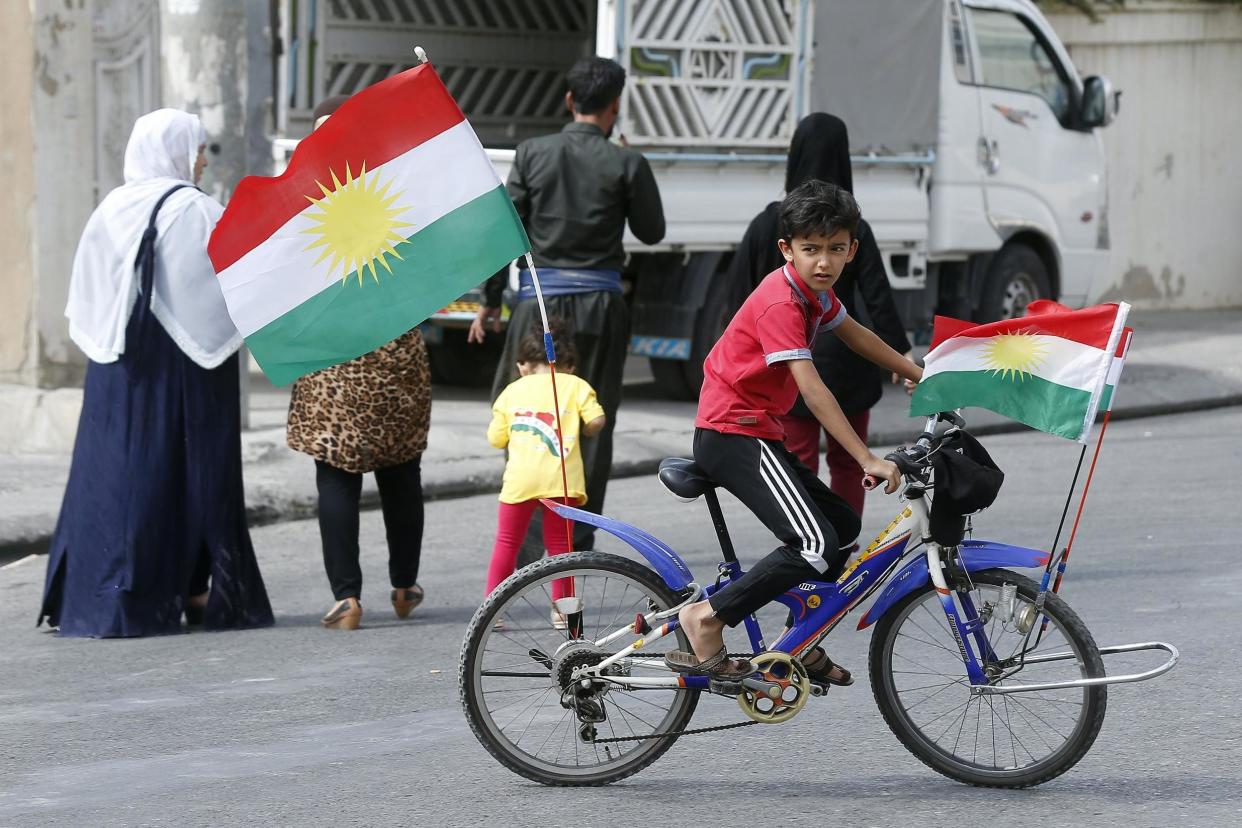 Vote: A child rides a bicycle with Kurdistan flags outside a polling station during the referendum: EPA