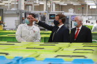 French President Emmanuel Macron, center, wearing a protective face mask, visits a factory of manufacturer Valeo in Etaples, , northern France, Tuesday May 26, 2020. Emmanuel Macron announced a 8 billion euro ($8.8 billion) plan Tuesday to save the country's car industry from huge losses wrought by virus lockdowns, including a big boost for electric vehicles. The plan includes government subsidies for car buyers and longer-term investment in innovative technology, especially in battery-powered cars. (Ludovic Marin, Pool via AP)