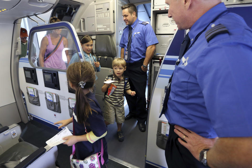 Captain Paul Bruder, right, welcomes Callum Price, center, and his family on board the aircraft, Saturday, Sept. 21, 2013 in New York. Dozens of families with children with autism have practiced air travel at New York's Kennedy International Airport. JetBlue Airways and the nonprofit Autism Speaks held the practice run for families at JFK on Saturday. (AP Photo/Mary Altaffer)