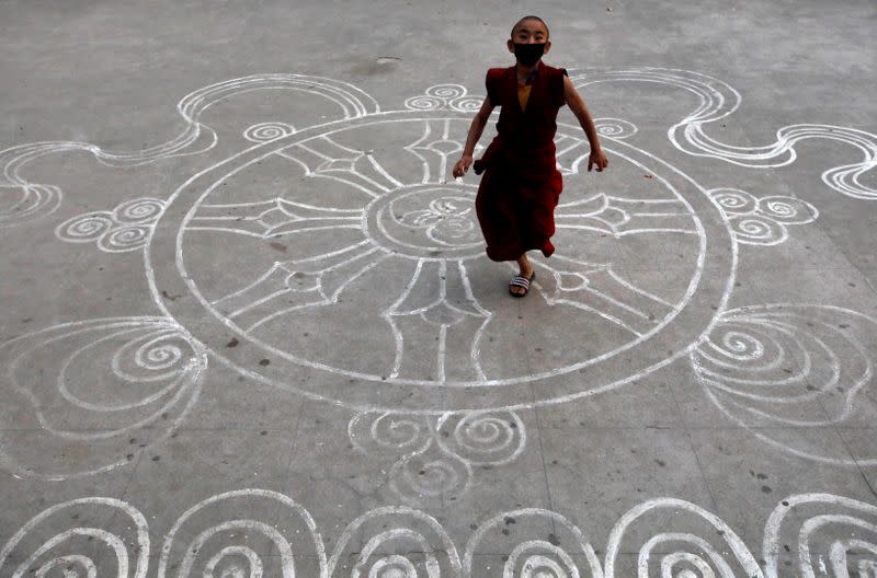 Novice monk wearing a protective mask runs at the premises of a monastery in Kathmandu