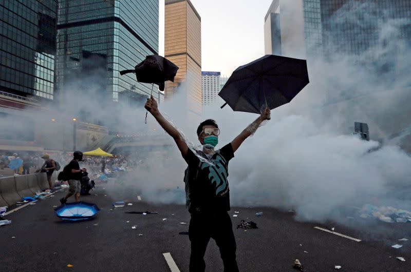A protester raises his umbrellas in front of tear gas which was fired by riot police to disperse protesters blocking the main street to the financial Central district outside the government headquarters in Hong Kong