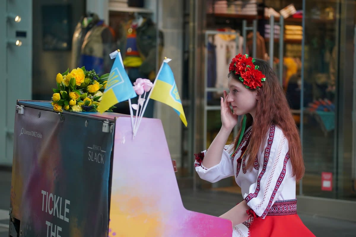 Ukrainian teenager, Alisa Bushuieva, who was forced to flee her country with her mother, Svitlana, in February last year, after playing piano to the crowd following a minute’s silence at Peter’s Lane in Liverpool ONE, to mark the one-year anniversary of the Russian invasion of Ukraine (PA)