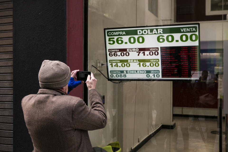 Un hombre toma una foto de una casa de cambio donde se muestran los valores de cambio de moneda 1 dólar cuesta 60 pesos argentinos a las 11:30 a.m.el 12 de agosto de 2019, en Buenos Aires, Argentina. Foto: Ricardo Ceppi / Getty Images. 