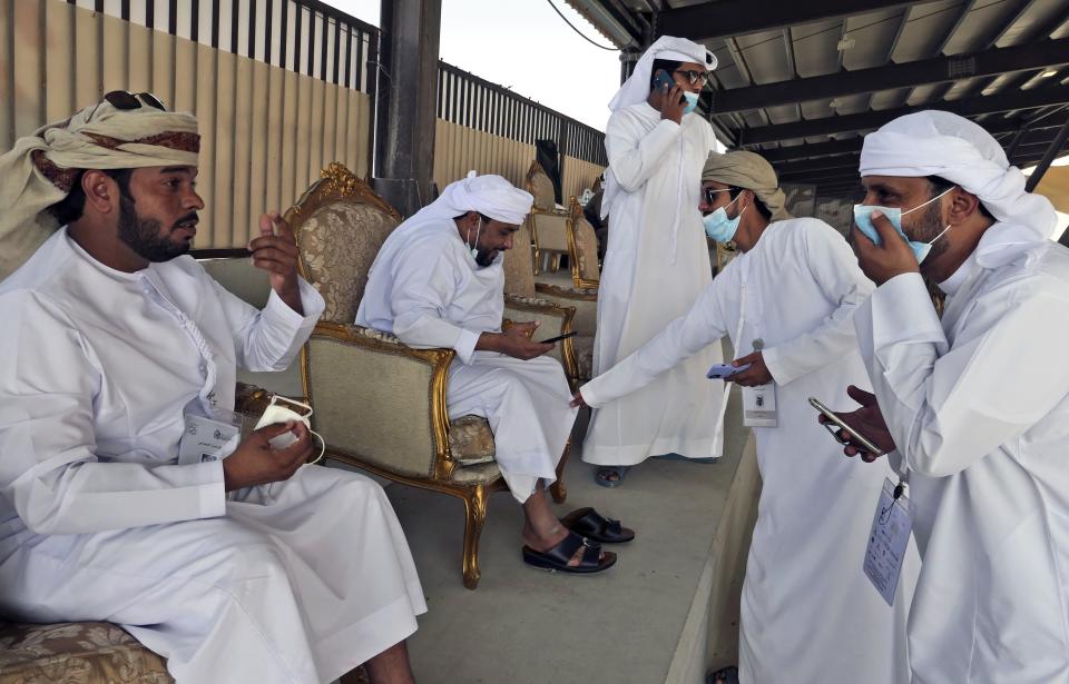 Camel owners chat before competition results are announced at Al Dhafra Festival in Liwa desert area 120 kilometres (75 miles) southwest of Abu Dhabi, United Arab Emirates, Wednesday, Dec. 22, 2021. Tens of thousands of camels from across the region have descended on the desert of the United Arab Emirates to compete for the title of most beautiful. (AP Photo/Isabel DeBre)