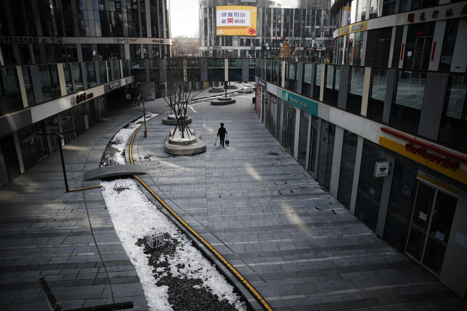 FILE - In this Feb. 10, 2020, file photo, a cleaner walks through a deserted compound of a commercial office building in Beijing. Chinese authorities are struggling to strike a delicate balance between containing a deadly viral outbreak and restarting the world’s second-biggest economy after weeks of paralysis. (AP Photo/Andy Wong, File)