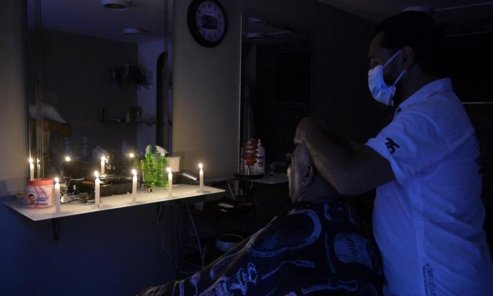 A man gets his hair cut in the dark at a barber shop in Beirut during a power cut caused by fuel shortages.