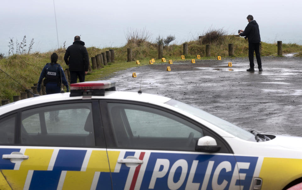 Police collect and photograph evidence in the carpark of the Te Toto Gorge lookout on Whaanga Rd, south of Raglan, New Zealand, Friday, Aug. 16, 2019. A manhunt was underway in New Zealand after an Australian tourist was killed following what police believe was a random attack on the van that he and his partner were sleeping inside.(Alan Gibson/New Zealand Herald via AP)