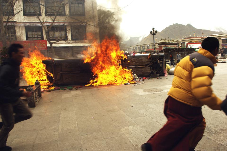 Photo obtained on March 22, 2008 shows a Tibetan m) running past burning vehicles, on March 14, 2008 in Lhasa, as the Tibetan capital erupted in deadly violence with security forces using gunfire to quell the biggest protests against Chinese rule in two decades.