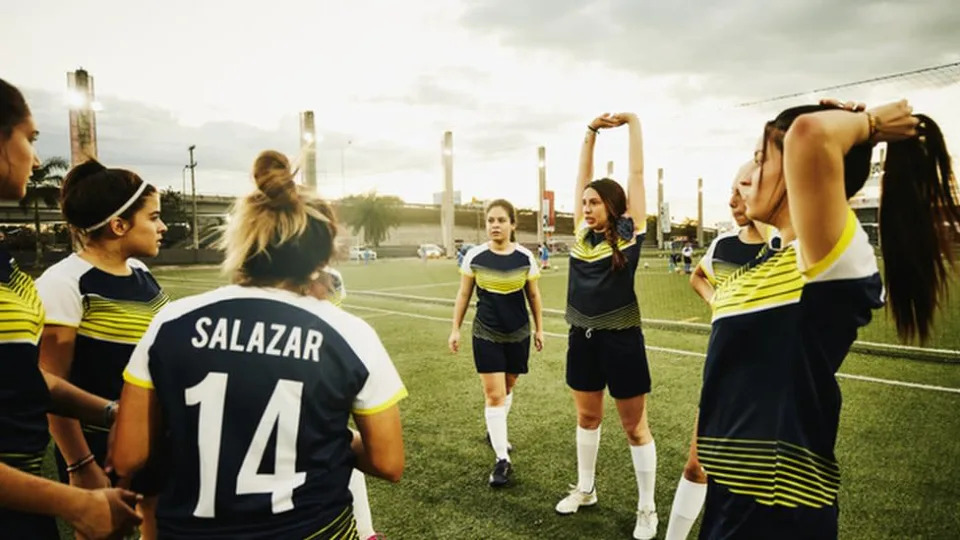 Equipe feminina de futebol se alongando no campo