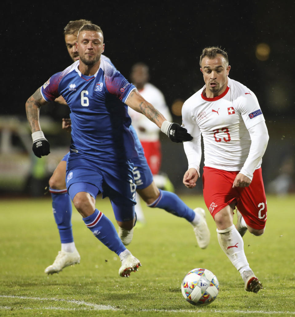 Switzerland's Xherden Shaqiri (23), right, is challenged by Iceland's Ragnar Sigurdsson (6), left, during the UEFA Nations League soccer match between Iceland and Switzerland at Laugardalsvollur stadium in Reykjavik, Iceland, Monday Oct. 15, 2018. (AP Photo/Brynjar Gunnarsson)