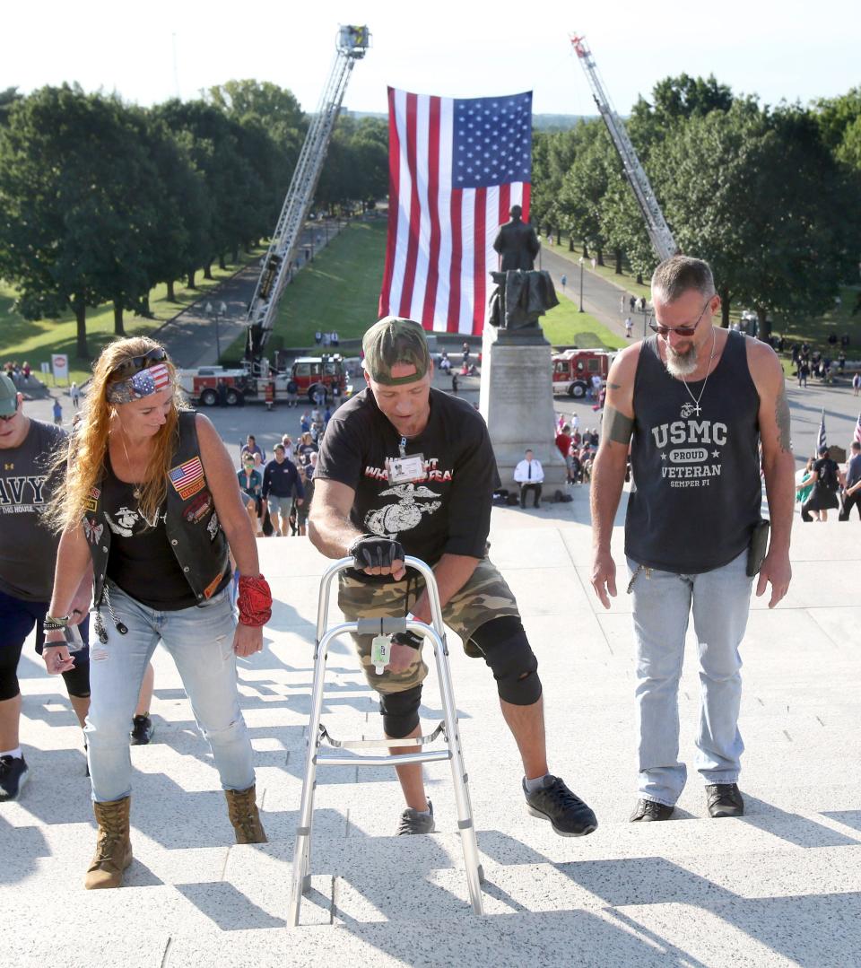 Joanne Smith, left, and Andy Kennard, right, look on as Adam Davis, center, participates in the Memorial Climb on the steps of the McKinley Presidential Library & Museum in Canton on Saturday. The event marked the 20th anniversary of the 9/11 attacks and recalled the memory of the 343 firefighters who lost their lives that day.