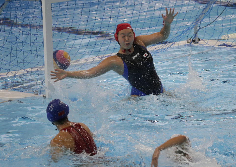 Japan's goal keeper Minami Shioya, center, fails to stop a shot from China's Niu Guannan, left, during their women's tournament group A water polo match at the 18th Asian Games in Jakarta, Indonesia, Friday, Aug. 17, 2018. (AP Photo/Lee Jin-man)