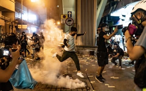 A protester attempts to kick a tear gas canister during a demonstration on Hungry Ghost Festival day in Sham Shui Po district  - Credit: Getty