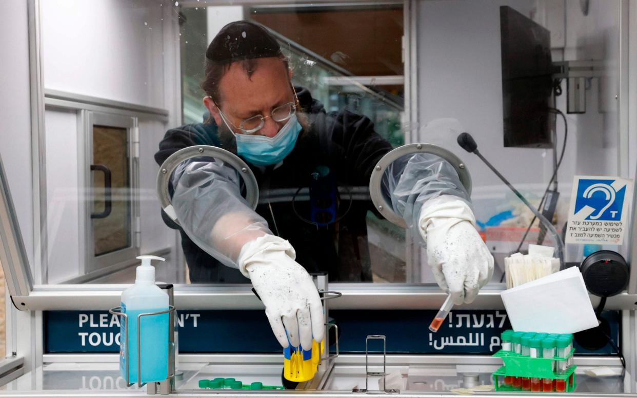 A medic collects a swab sample from a traveller at a booth at the COVID-19 coronavirus rapid testing centre in Israel's Ben-Gurion Airport  - AFP