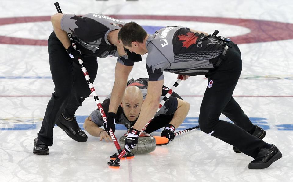 Canada's Ryan Fry, center, delivers the rock while teammates Ryan Harnden, left, and E.J. Harnden, right, sweep the ice during the men's curling gold medal game against Britain at the 2014 Winter Olympics, Friday, Feb. 21, 2014, in Sochi, Russia. (AP Photo/Wong Maye-E)