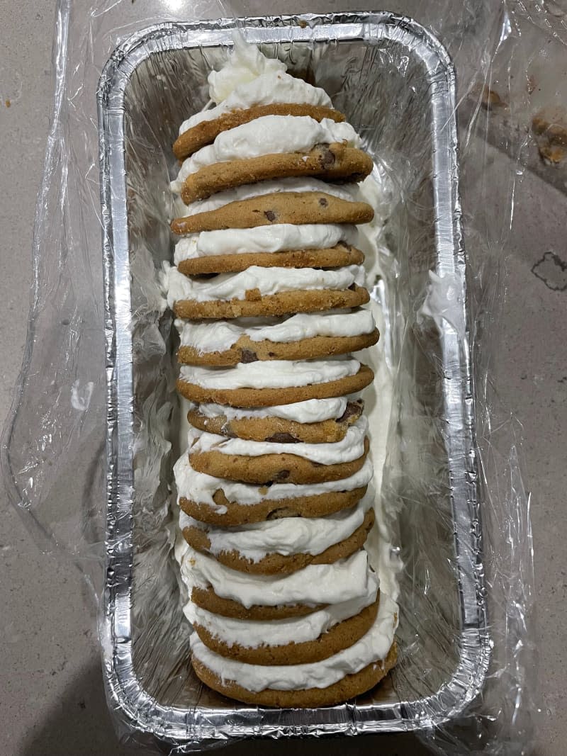 Cream sandwiched between chocolate chip cookies in baking pan.