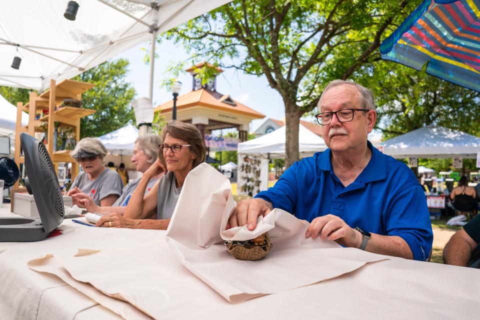 John Newby of Kentuck Red Dog Potters wraps an art piece purchased at the 2022 Druid City Arts Festival in Government Plaza, Saturday May 21, 2022. [Photo/Will McLelland] 