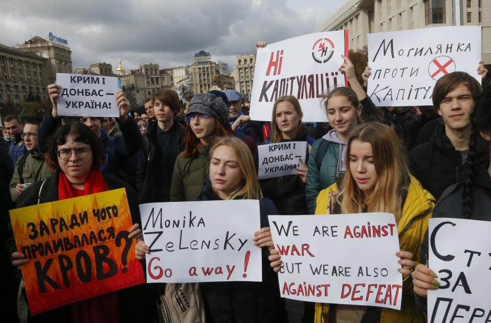 Protesters hold posters reading: "What did we spill our blood for?", "No capitulation", "Crimea, Donbas, Ukraine" as they gather in Independence Square in Kyiv, Ukraine, Sunday, Oct. 6, 2019. Thousands are rallying in the Ukrainian capital against the president's plan to hold a local election in the country's rebel-held east, a move seen by some as a concession to Russia. (AP Photo/Efrem Lukatsky)
