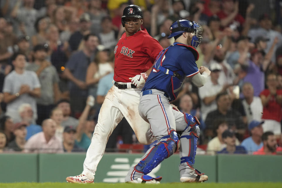 Boston Red Sox's Rafael Devers, left, scores near Texas Rangers' Jonah Heim, right, on a two-run single hit by Enrique Hernandez in the seventh inning of a baseball game, Thursday, July 6, 2023, in Boston. (AP Photo/Steven Senne)