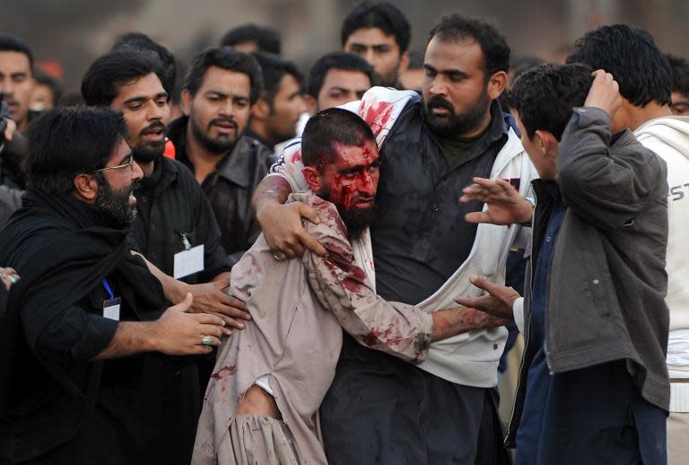 Pakistani Shiite Muslims assist an injured Sunni Muslim following clashes during an Ashura procession in Rawalpindi on November 15, 2013